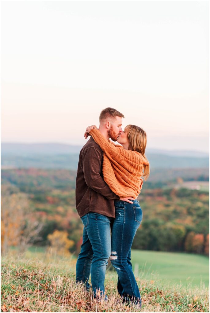 couple kissing on a hill at engagement session overlooking the West Virginia mountains