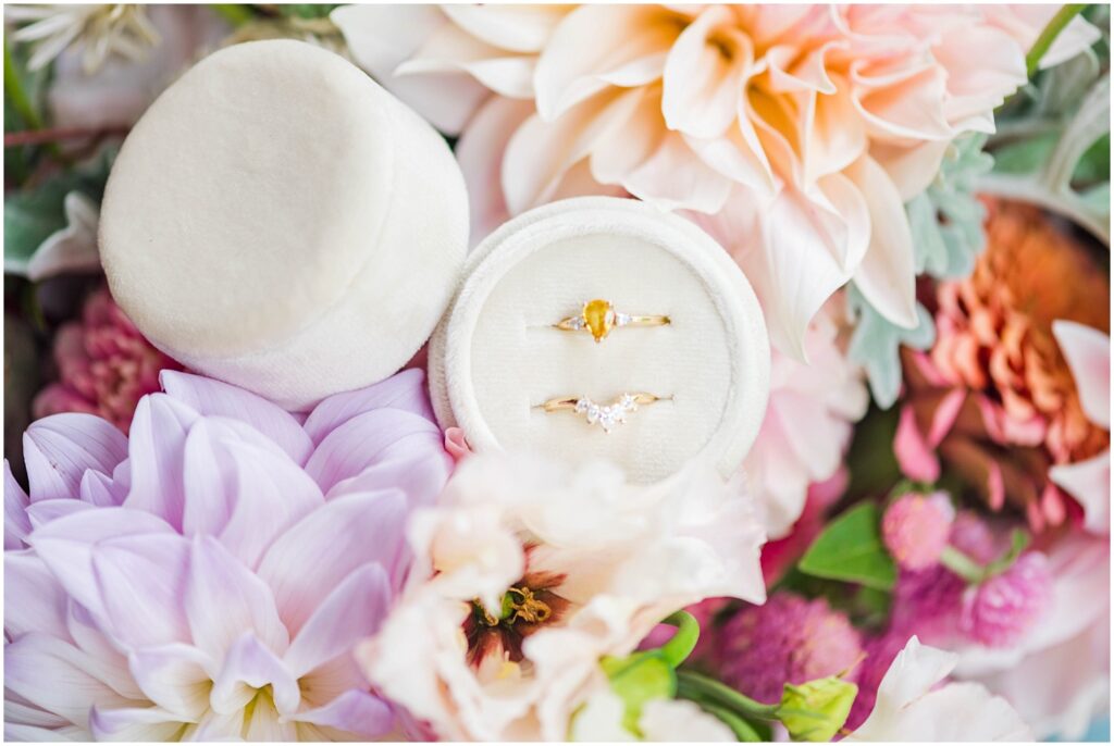 bride's wedding rings sitting in an ivory box on top of her bouquet