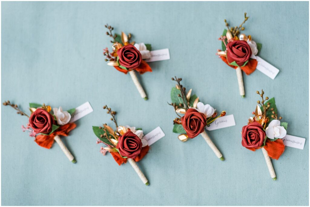 dark orange wood flower boutonnieres sitting on a blue styling mat