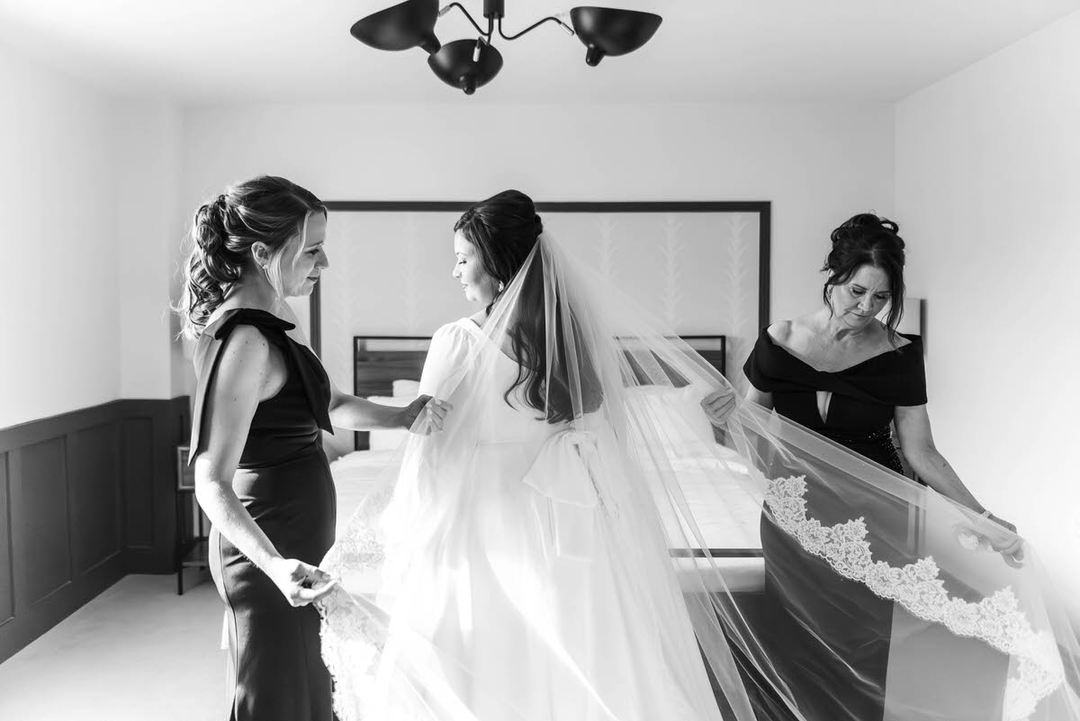 two bridesmaids helping bride adjust her veil at hotel morgan