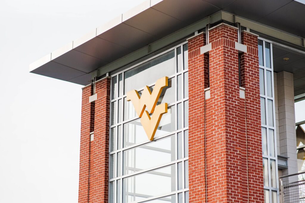 wvugradphotos04 carrie white photography brick office building facade with a large yellow w shaped logo on a glass wall logo on the glass façade between brick columns