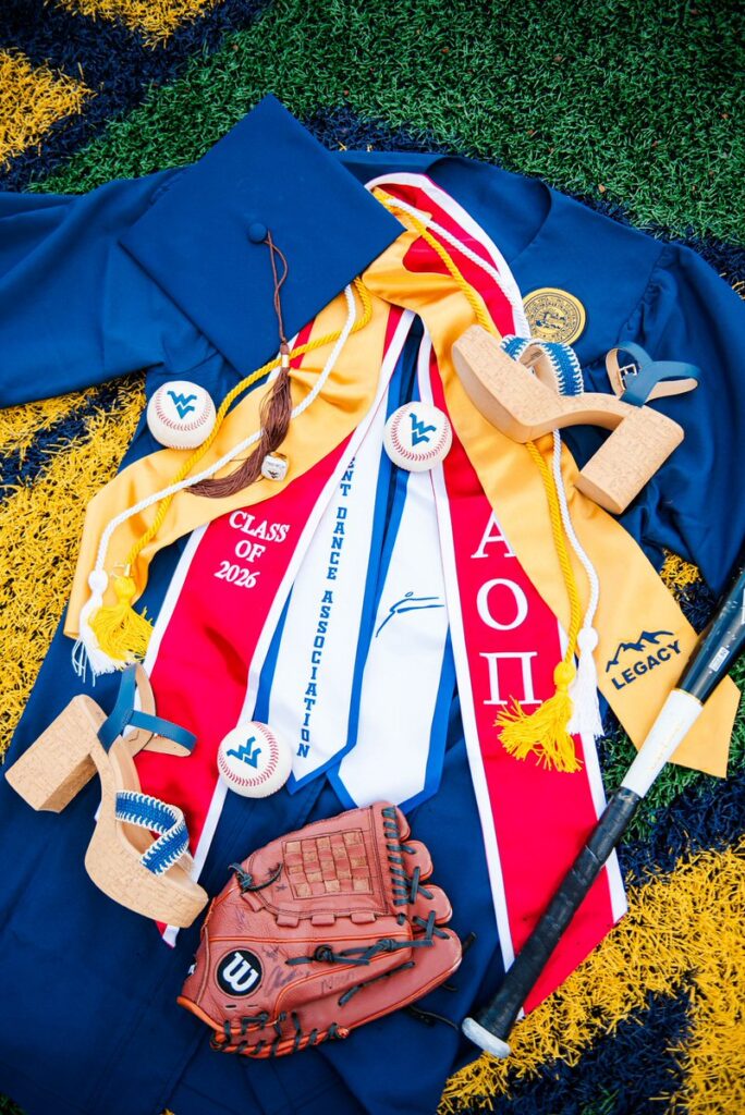 blue graduation gown with colorful stoles and cap plus a baseball glove balls and a bat on a sports field backdrop