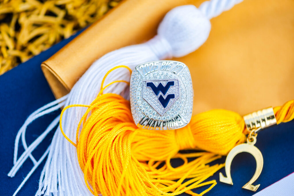 wvubaseballgradphotos55 carrie white photography close up of a sparkling wrestling championship belt with a blue emblem resting on orange cords and a blue background