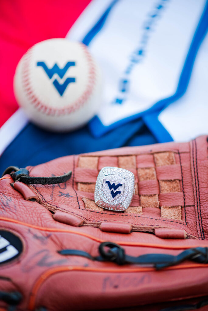 wvubaseballgradphotos74 carrie white photography close up of a pink baseball glove with a silver wv logo pin and a white baseball in the background showing a blue wv mark