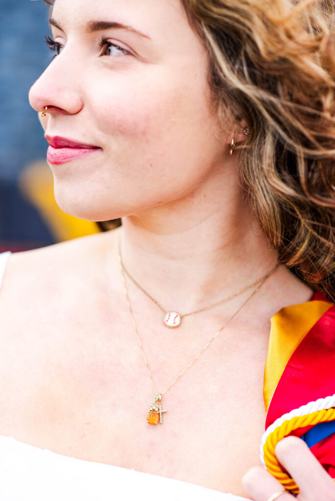 wvubaseballgradphotos88 carrie white photography close up of a womans profile showing a gold nose stud hoop earring and layered necklaces with a colorful scarf nearby