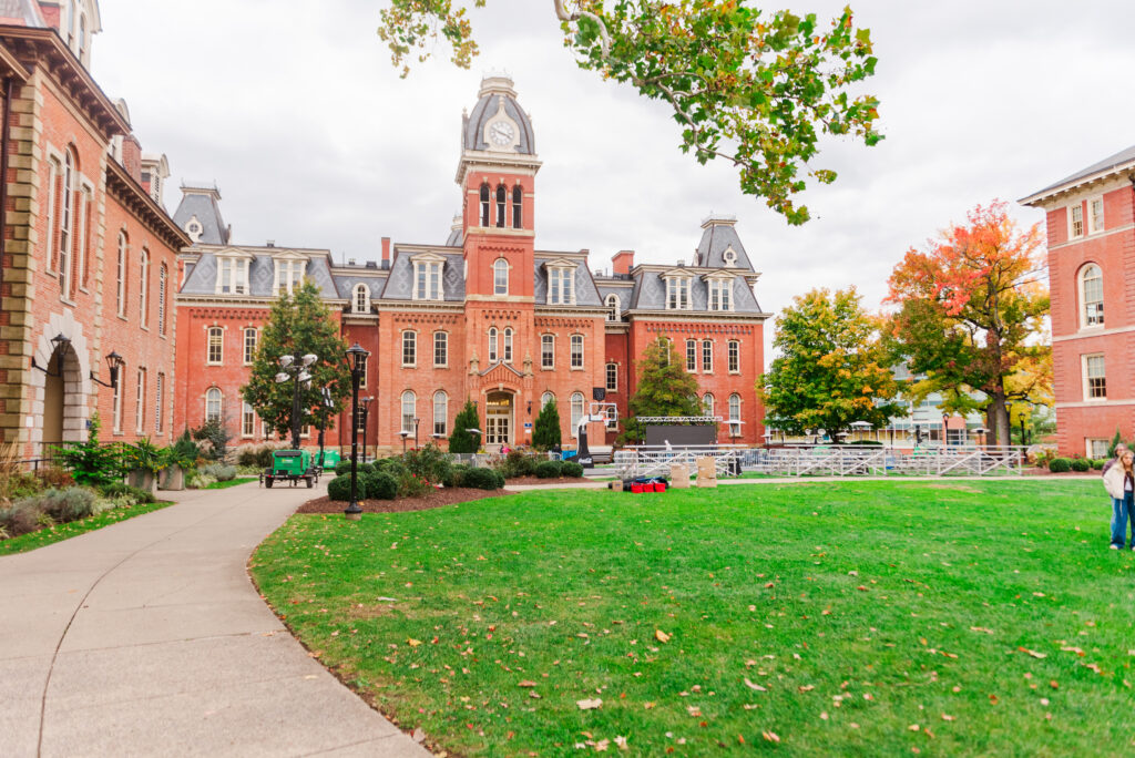 wvudecembergradphotos22 carrie white photography campus courtyard with red brick buildings a central clock tower and autumn trees outdoor event setup on the lawn